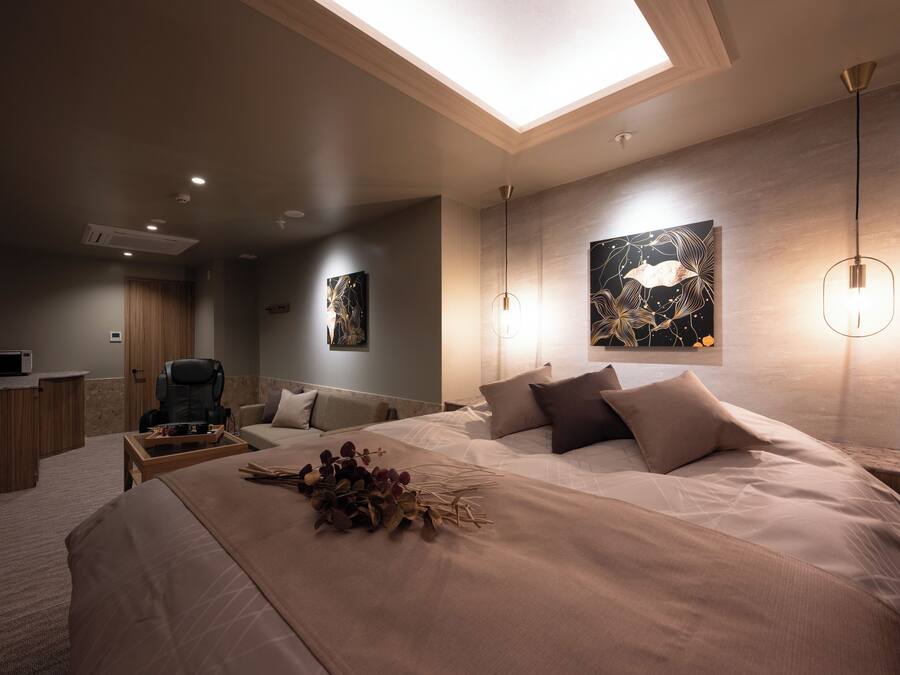 A modern bedroom with a skylight, a bed with a decorative arrangement, a desk, and artwork on the walls.