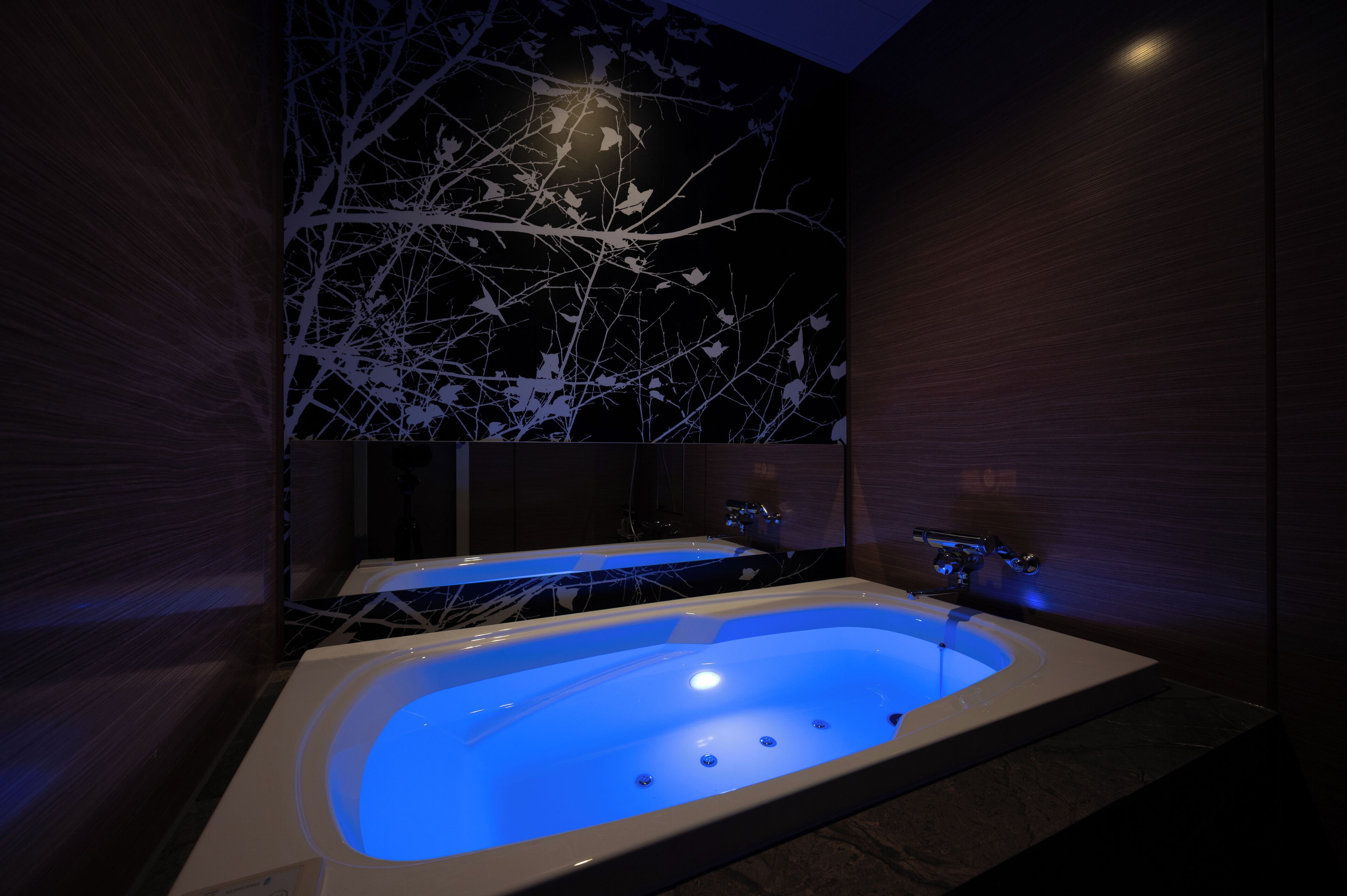Ein modernes Badezimmer mit einer freistehenden Badewanne, einem großen Spiegel und einem wandmontierten Waschbecken.