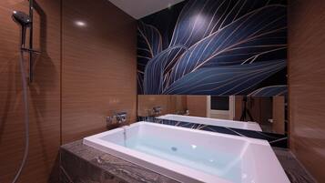 A modern bathroom with a large bathtub, a shower, and a wall with a leaf pattern.