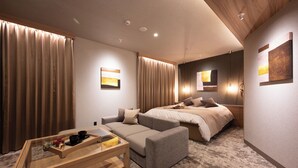 A hotel room with a sofa, a bed, a small table with a tray, and artwork on the walls. - HOTEL ZEN narahourai (Nara)