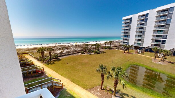Ein Resort mit Blick auf den Strand, einem Pool und einem mehrstöckigen Gebäude mit Balkonen.