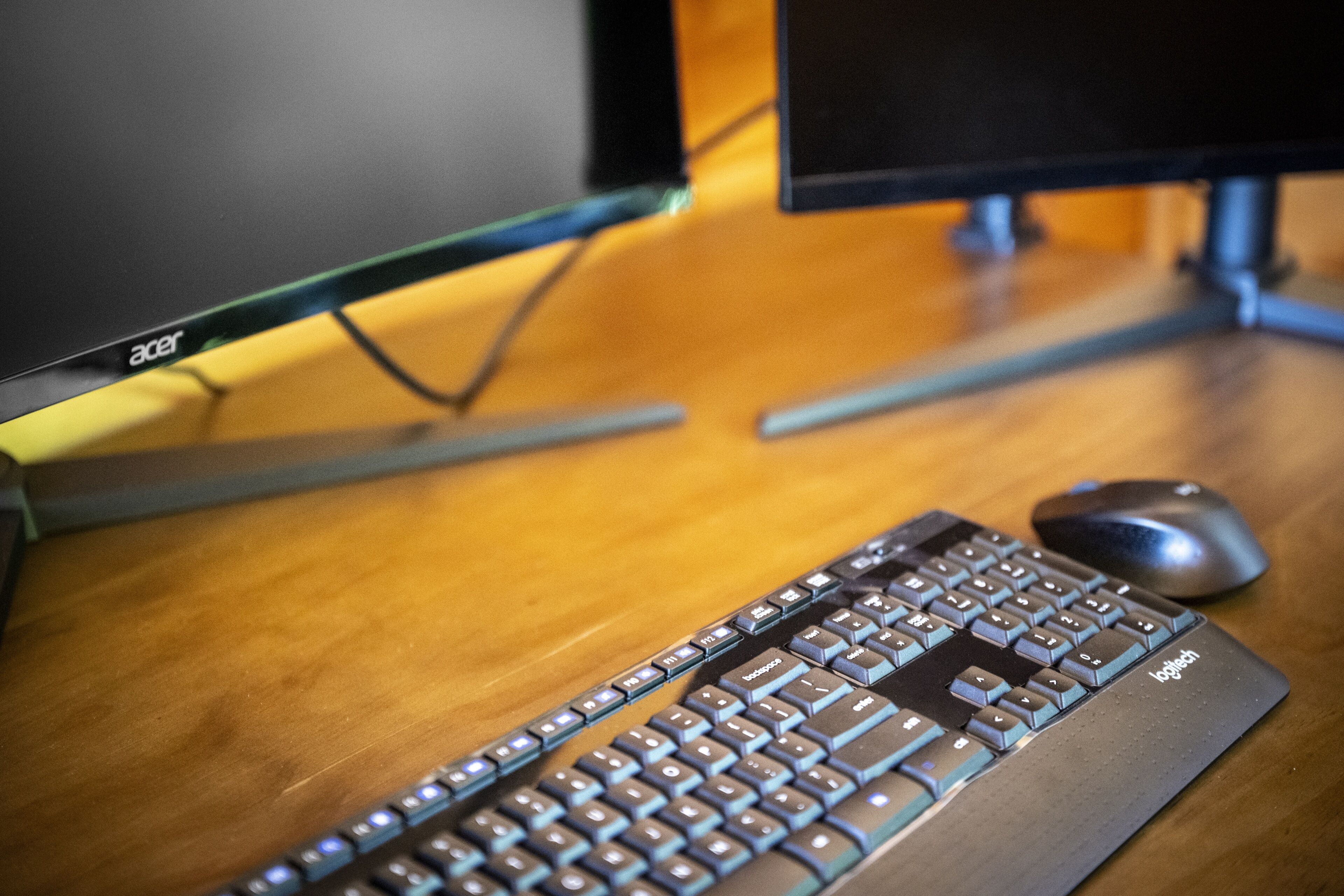 A keyboard and mouse on a wooden desk.
