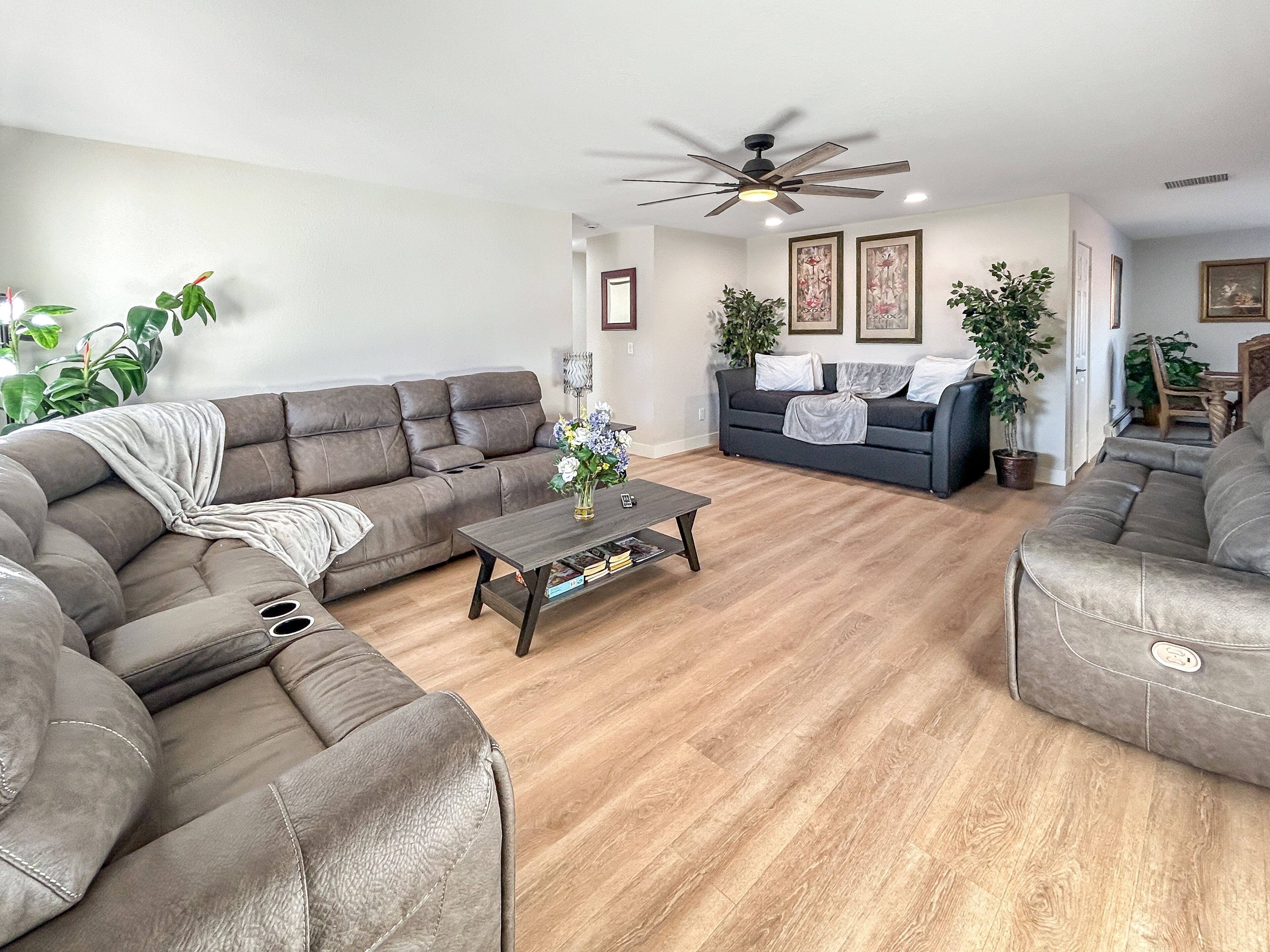 A modern living room with a grey sectional sofa, a coffee table, and a ceiling fan.