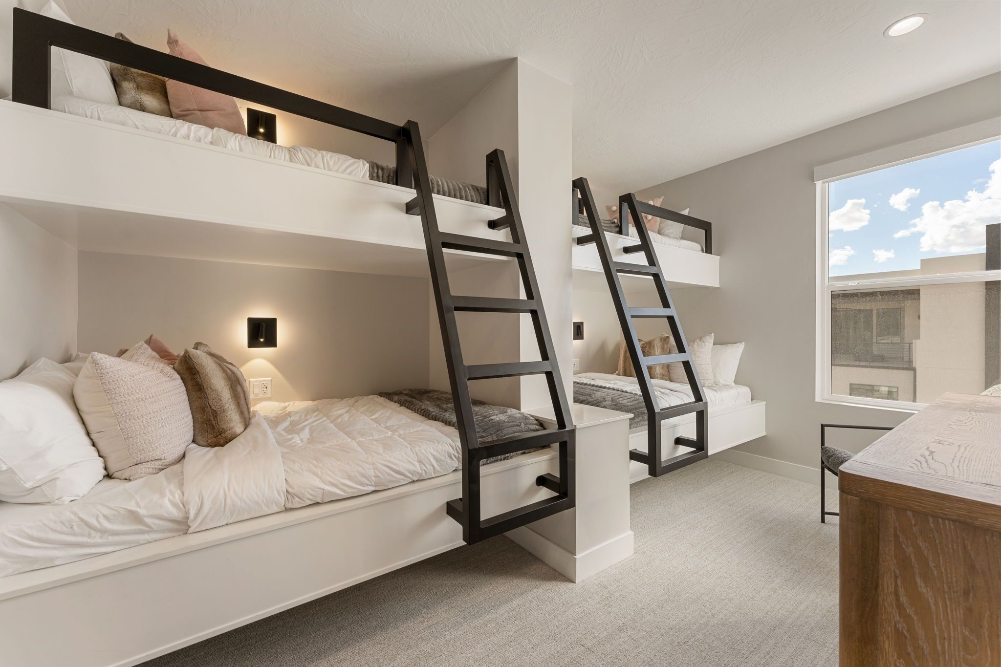 Habitación con literas, dos escaleras, una ventana y un escritorio.