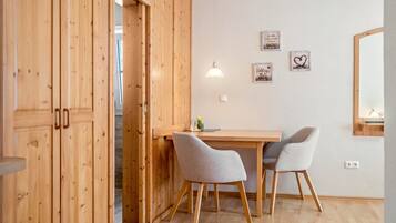 A room with wooden walls, a wooden desk, two grey chairs, a hanging lamp, and a mirror on the wall.