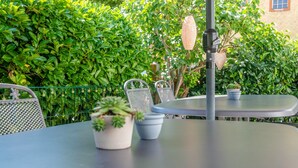 Un espace extérieur aménagé avec une table et des chaises, entouré d’une végétation luxuriante.