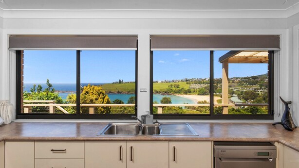 A kitchen with a view of a coastal landscape, including a beach and houses in the distance. - Ohana Oasis, Kiama, South Coast (Kiama)
