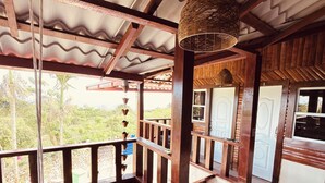 A wooden deck with a corrugated metal roof, a hanging woven light fixture, and a view of greenery outside. - Charming Villa with Atlantic Ocean view (Cabrera)