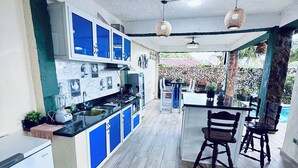 A modern kitchen with blue cabinets, a central island, and a dining area with wooden chairs. - Charming Villa with Atlantic Ocean view (Cabrera)