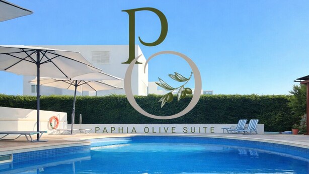 Piscina con sillones de descanso y sombrillas, identificada como la Suite Oliva Paphia.