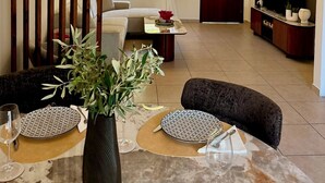 Una sala de estar moderna con comedor, un sofá, un televisor y una planta decorativa.