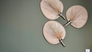 Un dormitorio con cama, almohadas, una mesita de noche con un florero y ventiladores de pared.
