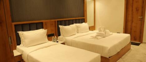 A hotel room with two beds, wooden headboards, and a large mirror.