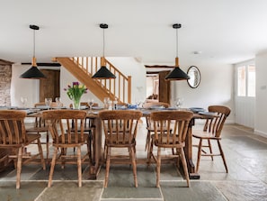 A dining area with wooden furniture, black pendant lights, and a staircase in the background. - Middle Dean Farmhouse (Barnstaple)