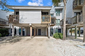 A multi-story residential building with balconies, a driveway, and a clear sky. - ENJOY GULF VIEWS from all three decks of this two bedroom townhome. (St. George Island)