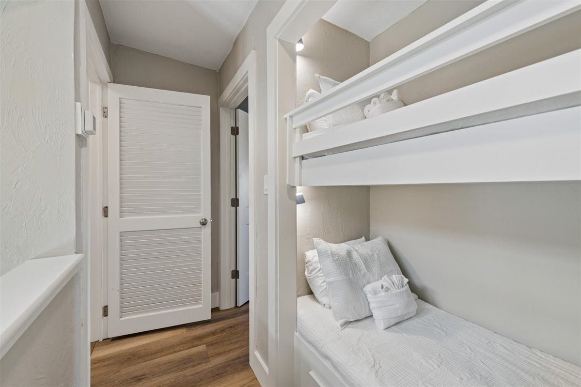 Quarto com beliche, porta e corredor.
