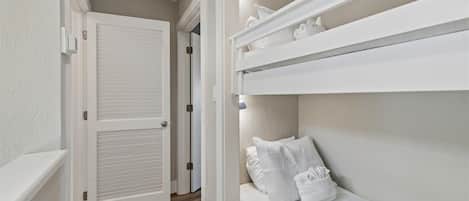 Quarto com beliche, porta e corredor.