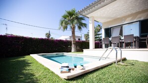 Una piscina con una tumbona, un patio cubierto y vistas a un edificio con terraza.