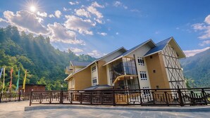 Un hotel moderno con una grande facciata in vetro, un balcone e vista su un paesaggio montuoso.