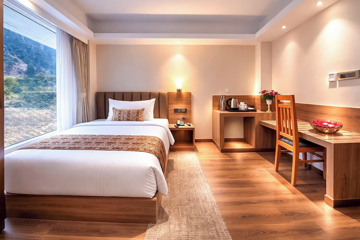 Una habitación de hotel con una cama grande, un escritorio y vistas al exterior.