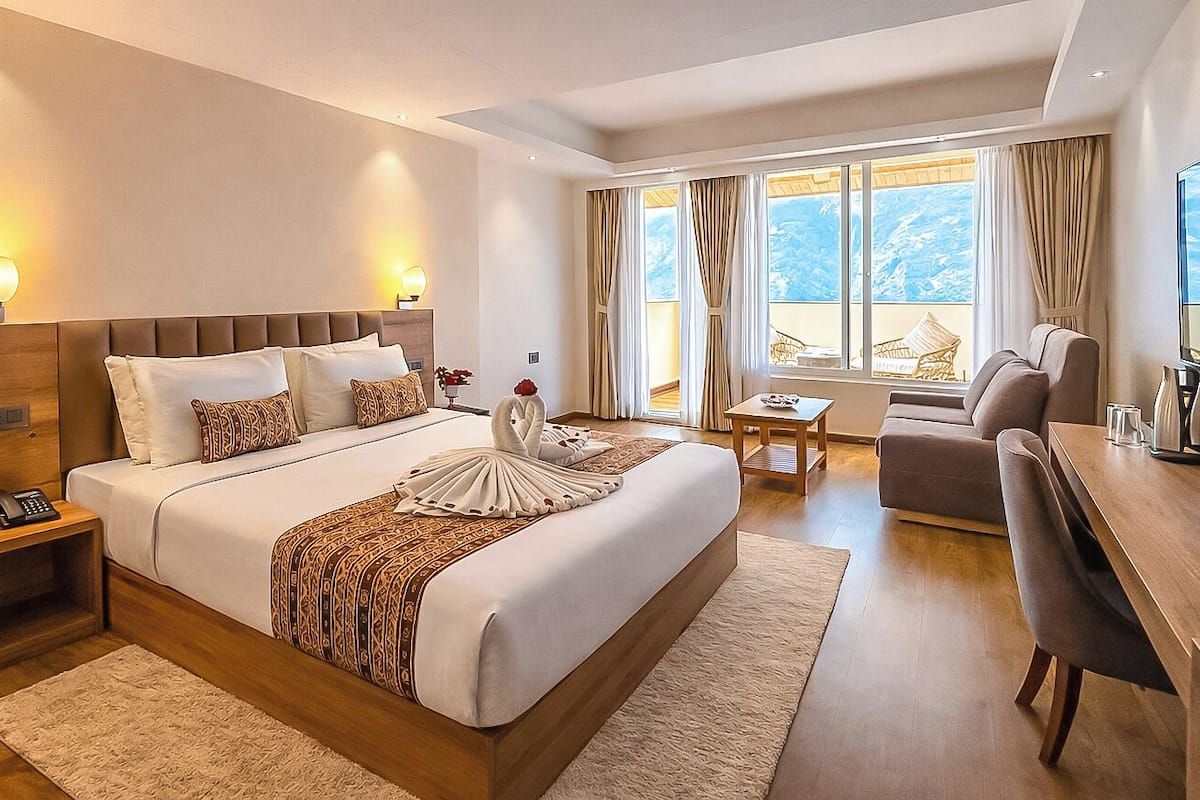 Habitación de hotel con una cama grande, mesitas de noche, un escritorio y vistas al exterior.