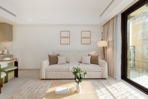 Un salon moderne avec un canapé, une table basse et un vase rempli de fleurs. Deux œuvres d’art encadrées ornent le mur, et une lampe se trouve à côté du canapé.