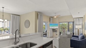 Eine moderne Küche mit doppelter Spüle, Geschirrspüler und einem Essbereich mit Blick auf den Strand.