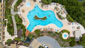 Ein Luftbild eines Resorts mit einem großen zentralen Pool, mehreren kleineren Pools und verschiedenen Sitzbereichen im Freien.