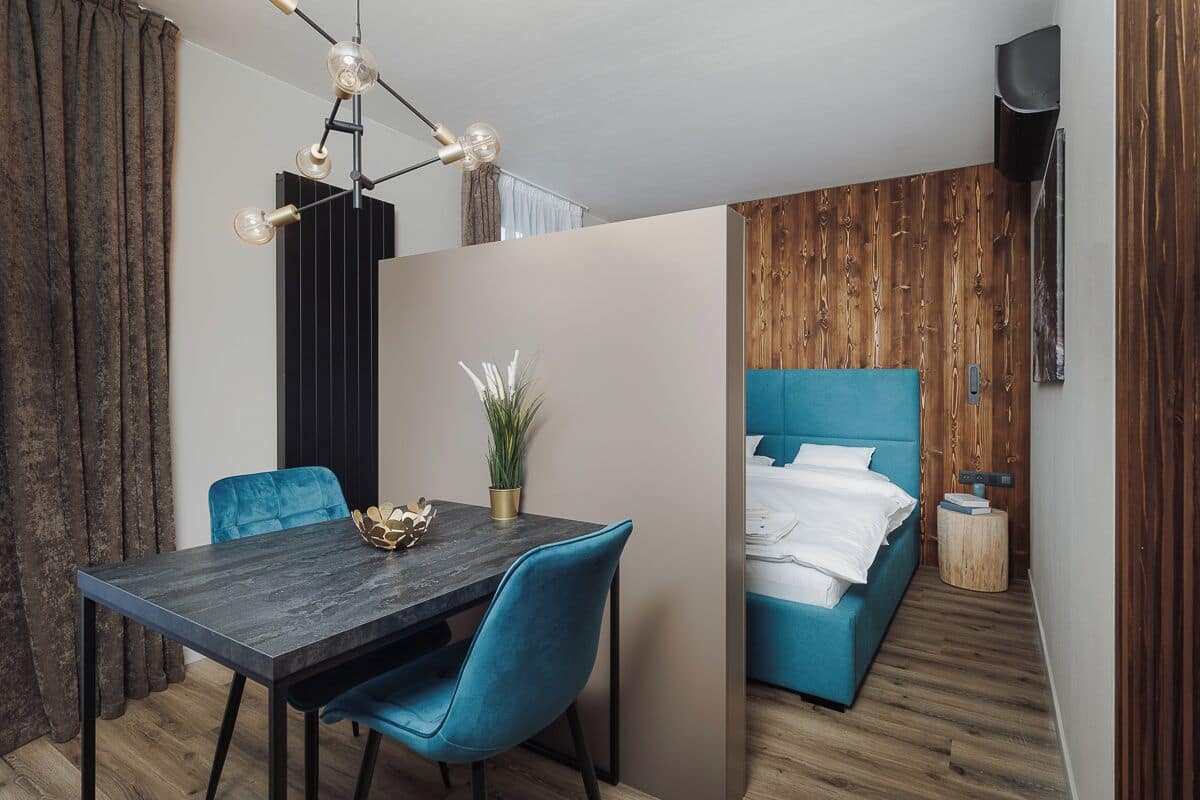 A modern room with a dining table, blue chairs, a blue sofa, and a wooden accent wall.