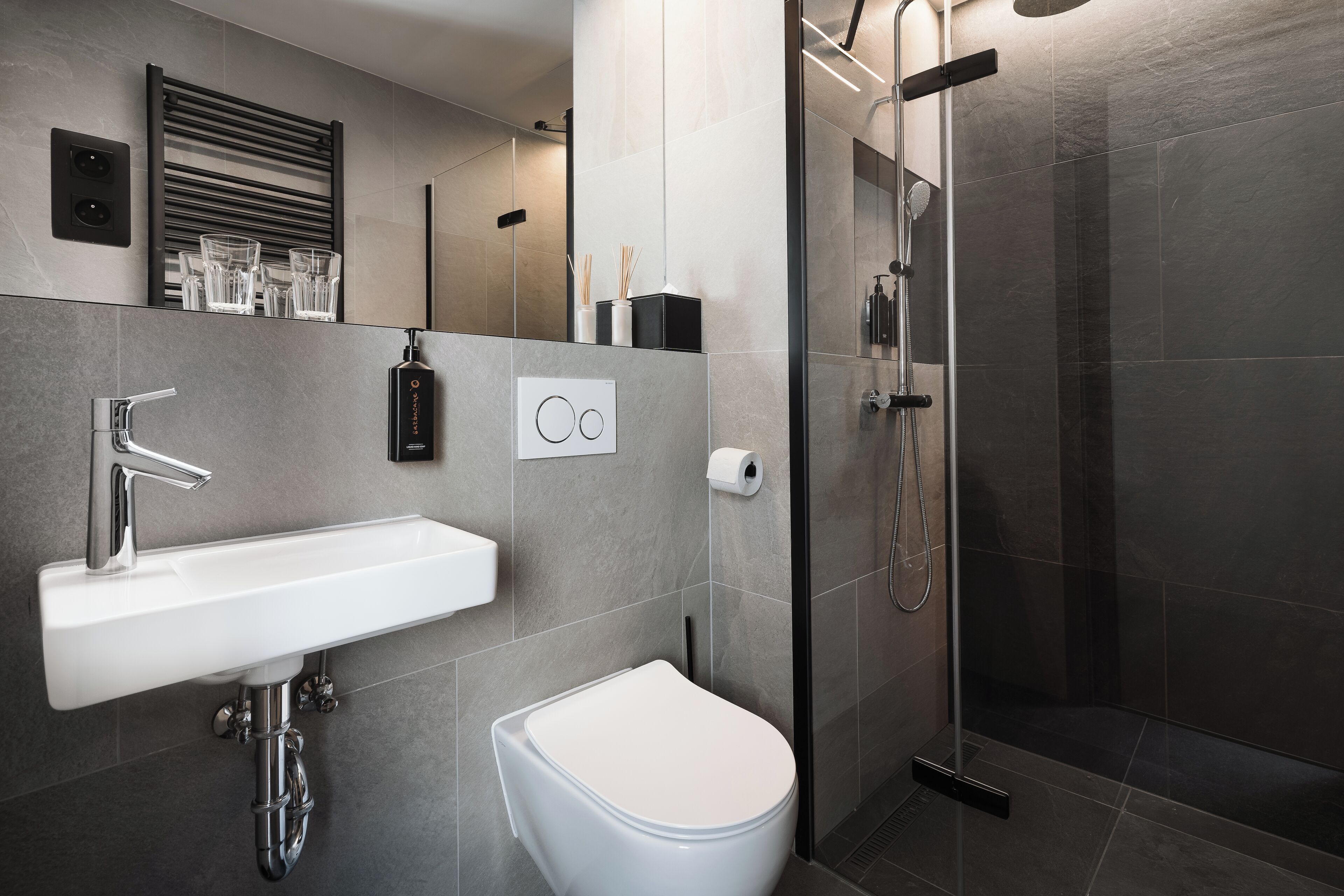 A modern bathroom with a white sink, a toilet, and a glass-enclosed shower.
