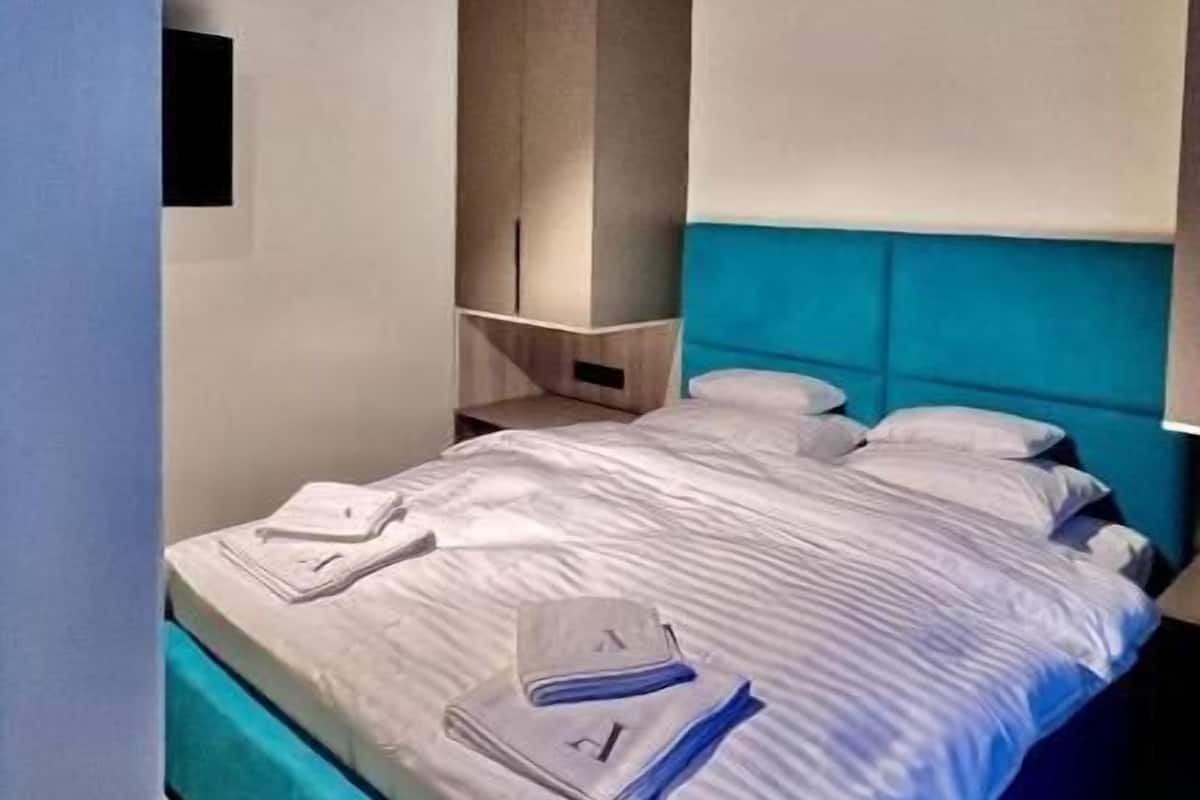 A bedroom with a bed, a nightstand, a wardrobe, and a wooden ceiling.