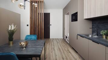 A modern kitchen with a dark countertop, wooden flooring, and a built-in microwave.