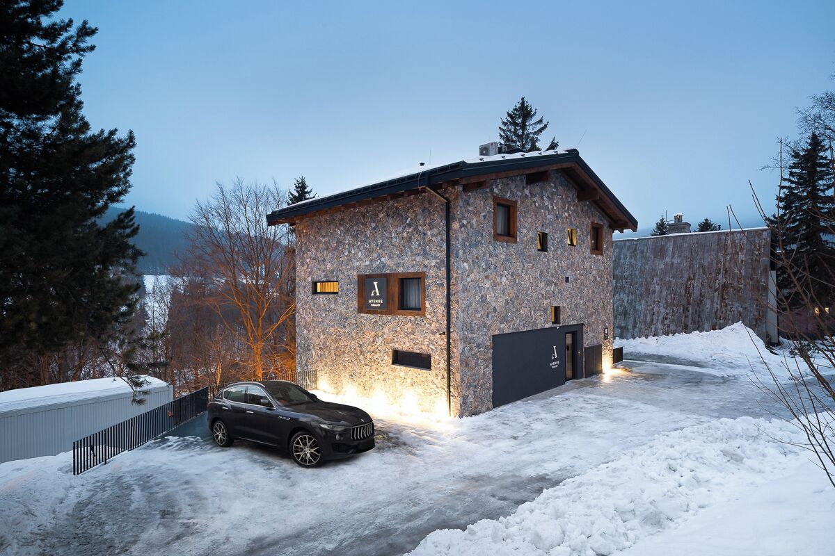 A stone building with a car parked in front, surrounded by snow.