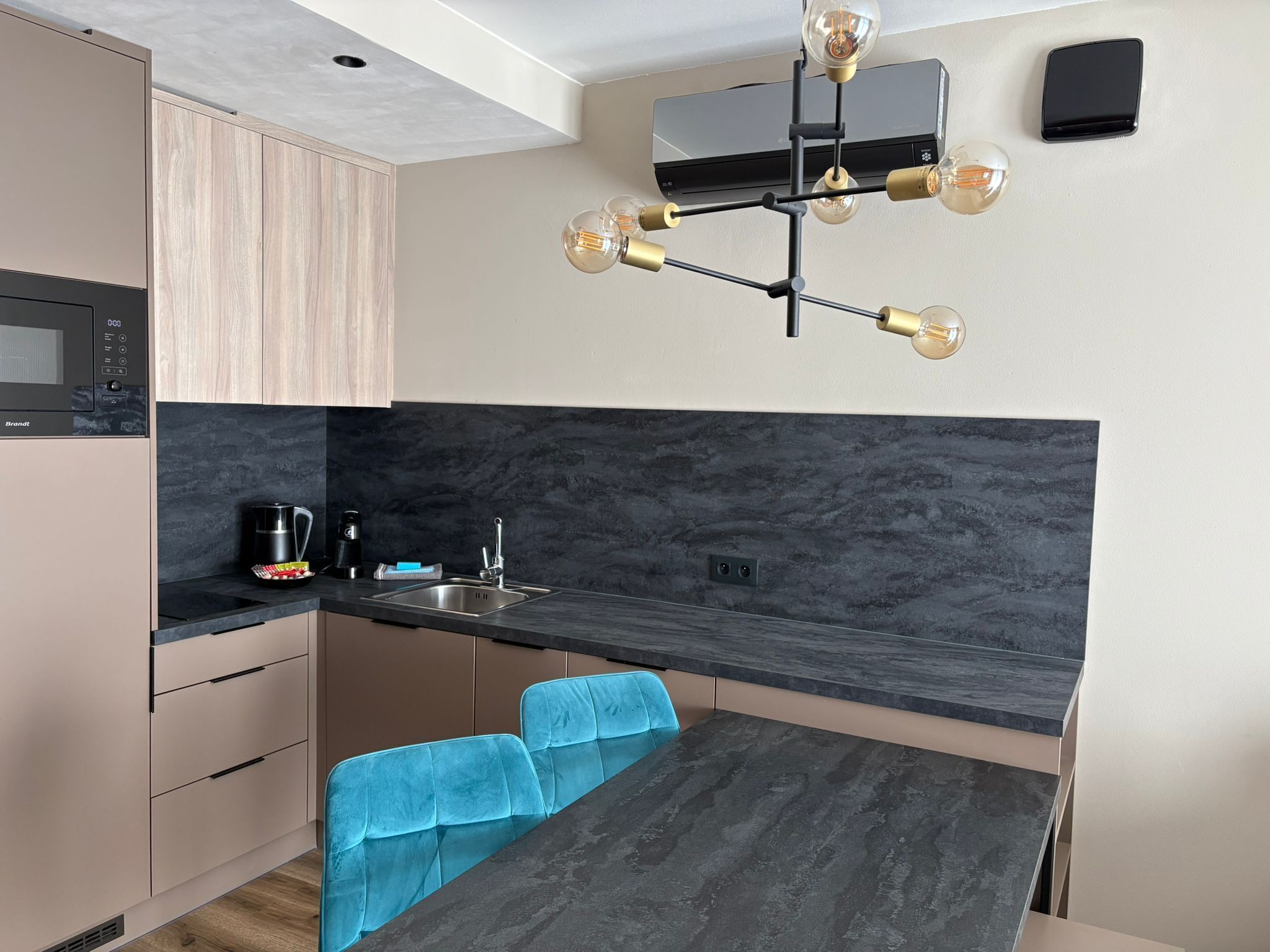 A compact kitchen with a modern design, featuring a built-in microwave, a sink, and a dining area with a table and chairs.