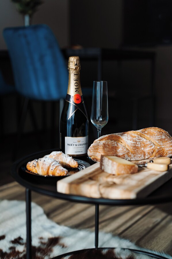 Une bouteille de champagne Moët & Chandon, un verre et une assiette avec des pâtisseries et du fromage, le tout posé sur une table.