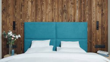 Ein Bett mit einem türkisfarbenen Kopfteil, weißer Bettwäsche und Holzvertäfelung an der Wand.