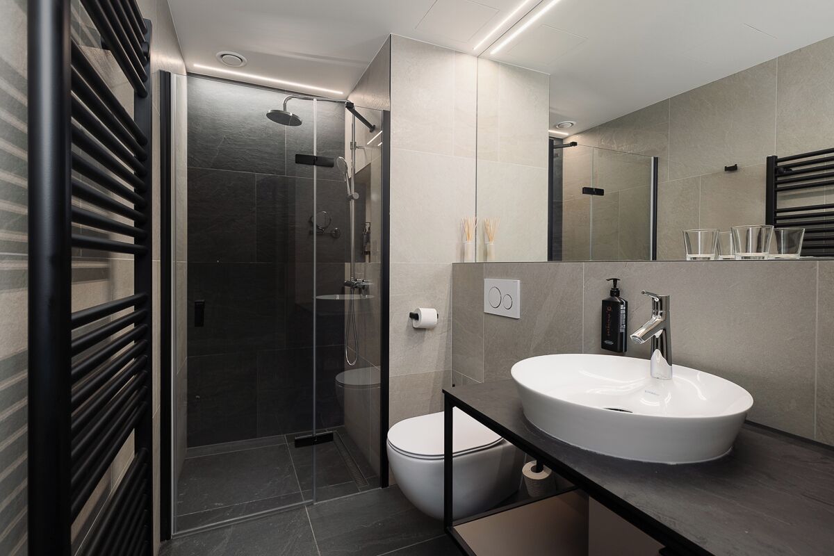 A modern bathroom with a glass-enclosed shower, a white sink, and a large mirror.