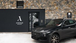 A black car parked in front of a building with a stone facade and a sign reading "Avenue Chalet Owner Parking". - Avenue Chalet (Špindlerův Mlýn)