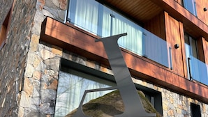 A modern building with stone and wood exterior, large windows, and a unique metal sculpture. - Avenue Chalet (Špindlerův Mlýn)