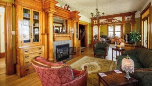 A spacious living room with a fireplace, wooden furniture, and a chandelier.