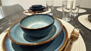 A dining table set with blue and gold plates, a gold fork, and clear glasses. - Modern Canal Side 1BR | Balcony | Near Wembley & Tube (Wembley)