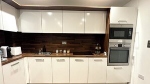 A modern kitchen with white cabinets, a wooden countertop, and built-in appliances including a microwave and oven. - Modern Canal Side 1BR | Balcony | Near Wembley & Tube (Wembley)