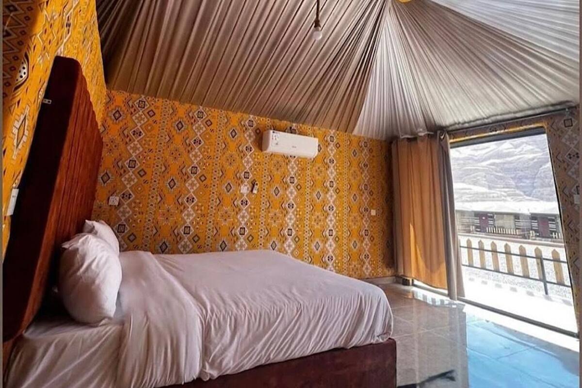 Una habitación con cama, pared con diseño y ventana con vistas.