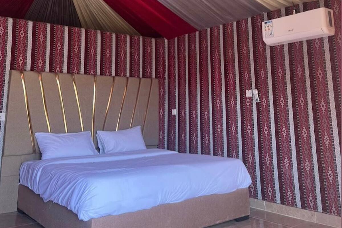 Una habitación de hotel con una cama grande, papel tapiz estampado y un ventilador de techo.