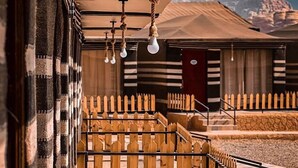 A model of a building with a wooden fence, a staircase, and a view of a mountainous landscape. - Victoria Luxury Camp (Wadi Rum)