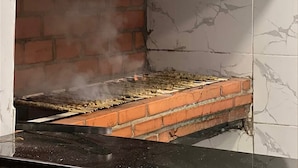 A brick grill with skewers of food being cooked, surrounded by a tiled wall. - Victoria Luxury Camp (Wadi Rum)