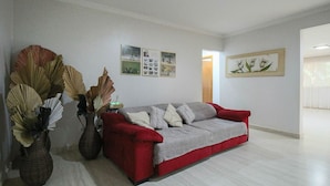 Una sala de estar con un sofá rojo, un abanico decorativo grande y una pared con cuadros.