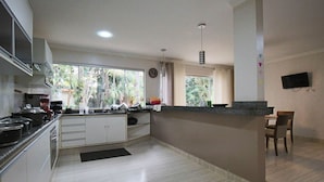 Una cocina moderna con una isla grande, armarios blancos y un comedor con mesa y sillas.