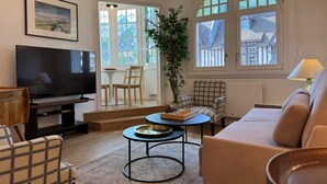 Un salon avec une télévision, un canapé, une table basse et une plante.