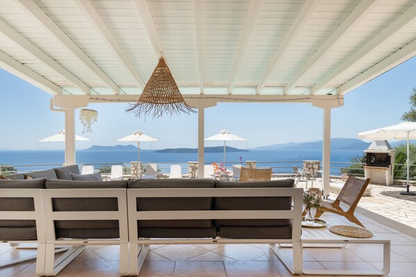 Un espacio de estar al aire libre con techo, que ofrece vistas al mar y a las montañas.